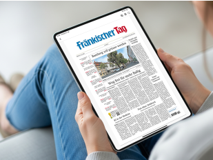 Zwei Frauenhaende halten ein Tablet. Zu sehen ist das ePaper des Fränkischen Tag auf dem Desktop.
