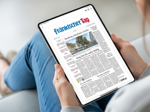 Zwei Frauenhaende halten ein Tablet. Zu sehen ist das ePaper des Fränkischen Tag auf dem Desktop.